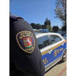 Strażnik Miejski a w tle pojazd służbowy